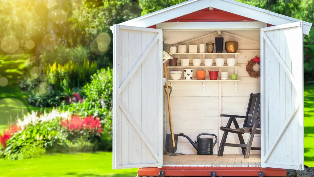 Un petit cabanon avec une chaise et un outil de jardin, situé dans un jardin bien entretenu.